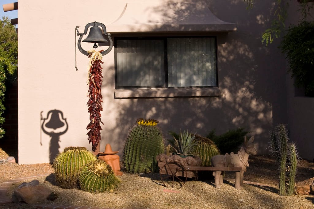 Zeroscaped Arizona front yard of bare gravel with a few barrel cacti and ornaments against a stucco wall