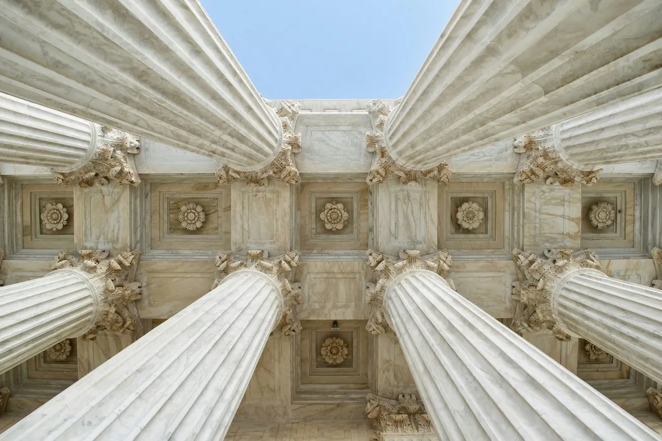 A photograph taken between the columns at the Supreme Court entrance, looking up.