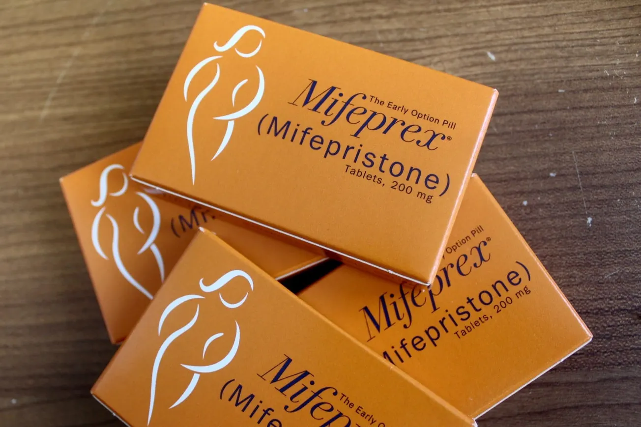 Four orange boxes of mifepristone on a wood table top
