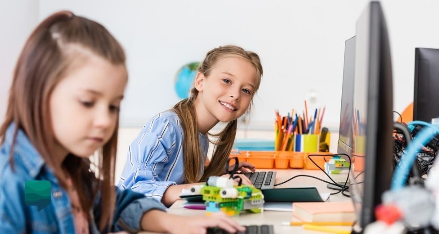 Como adotar aulas híbridas na sua Escola de Inglês ou Centro de Idiomas. Alunas com computador em sala de aula.