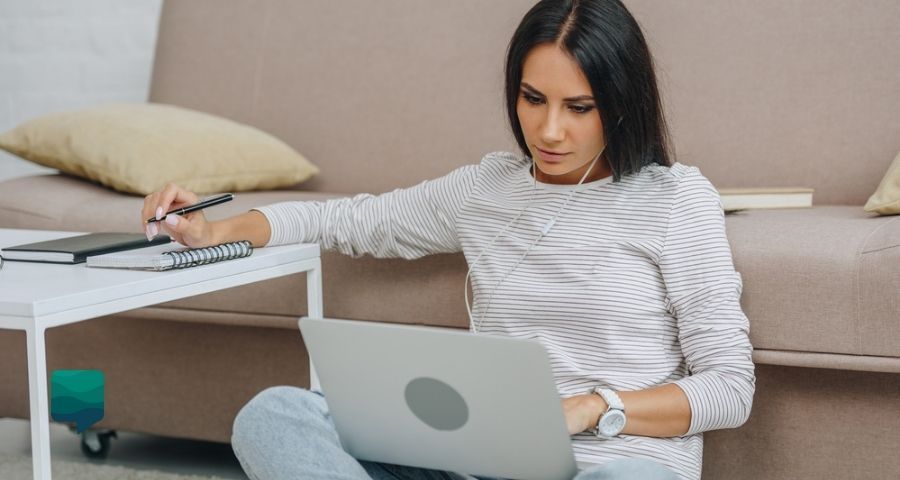 Entenda a diferença entre aula remota e educação a distância. Foto de uma mulher estudando com o notebook no colo.