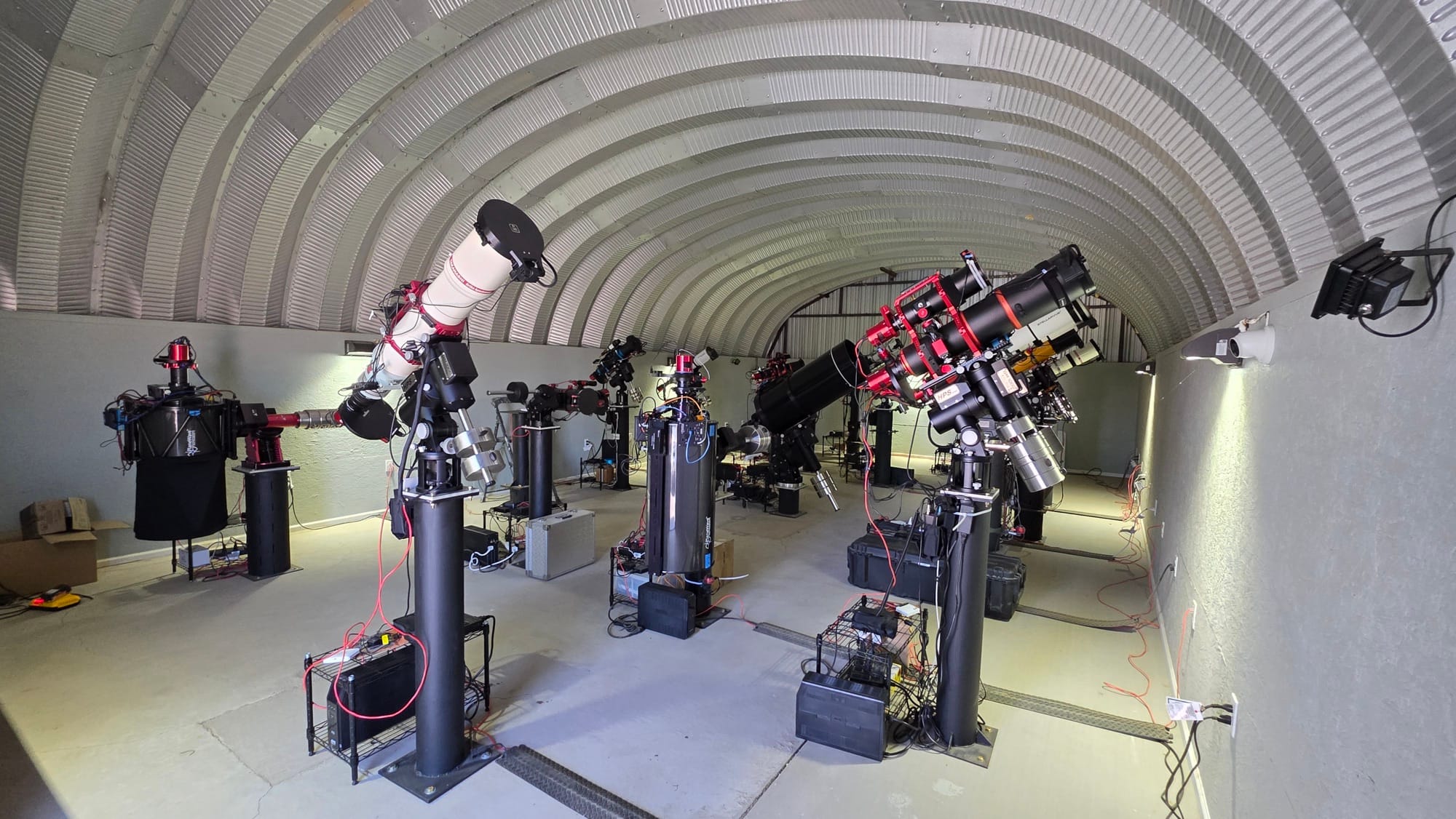 Looking down the length of Observatory 20, the half-pipe observatory, at telescopes mounted on black piers