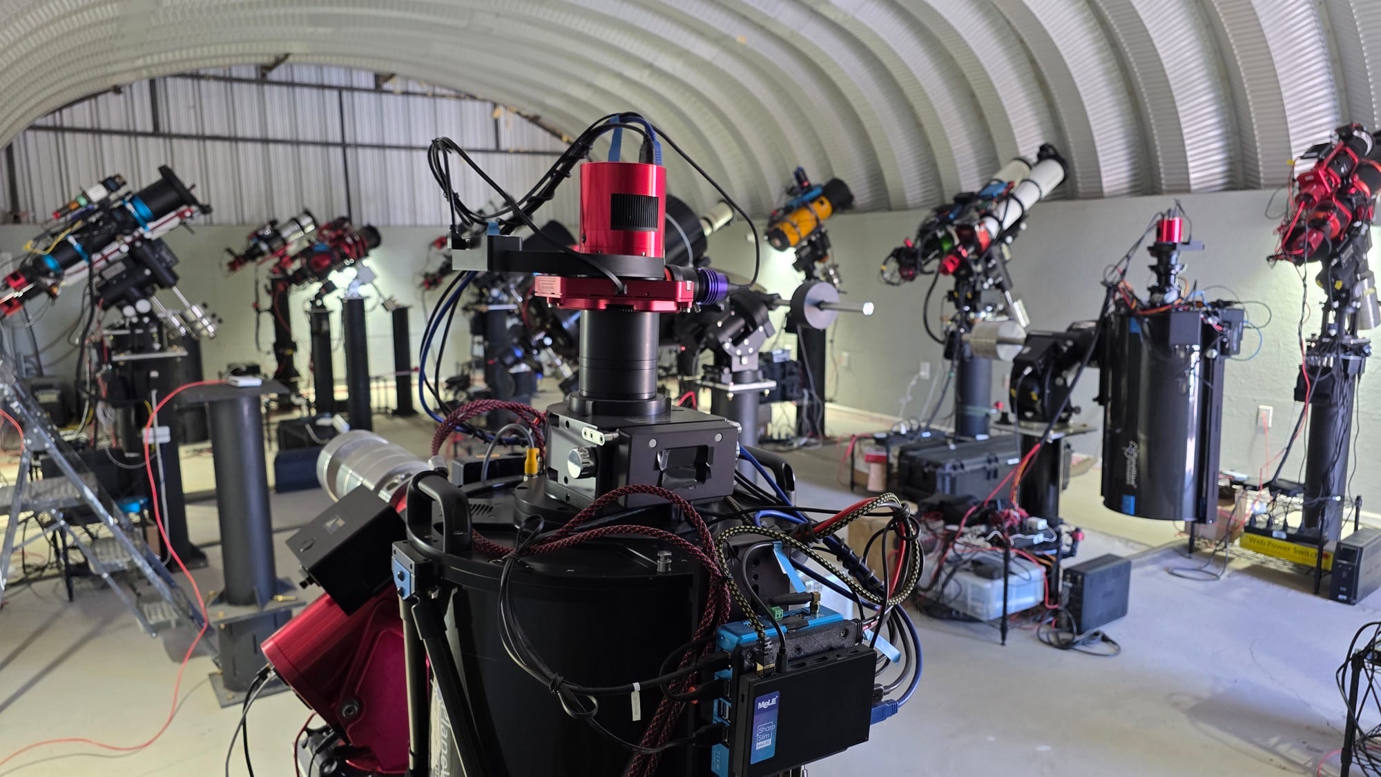 Rows of member telescopes and cameras on individual piers inside Observatory 20, the DSP Remote half-pipe observatory