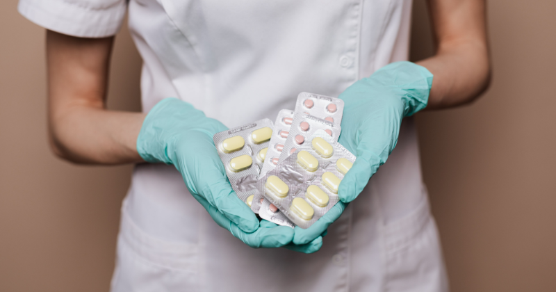 Hoitaja pitää käsissään lääkepakkauksia.