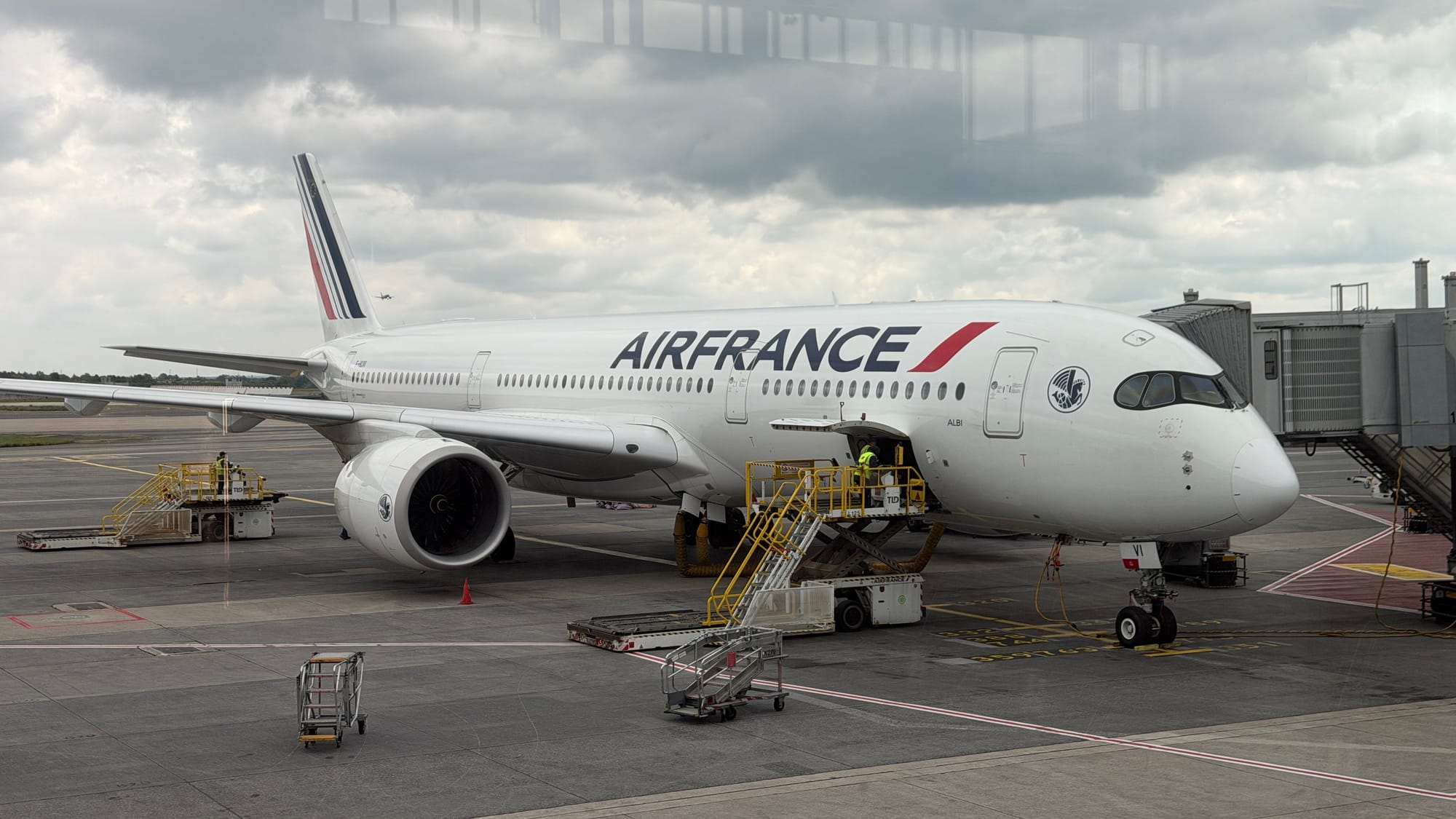 Air France Airbus A350 parked at an airport gate with ground crew and equipment around it