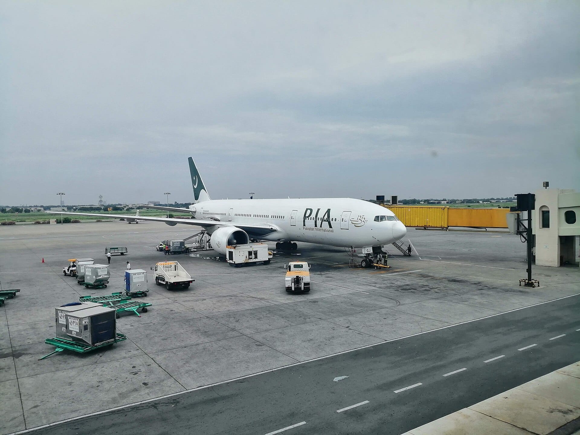 Pakistan International Airlines Boeing 777 parked at a gate at Lahore airport under a cloudy sky