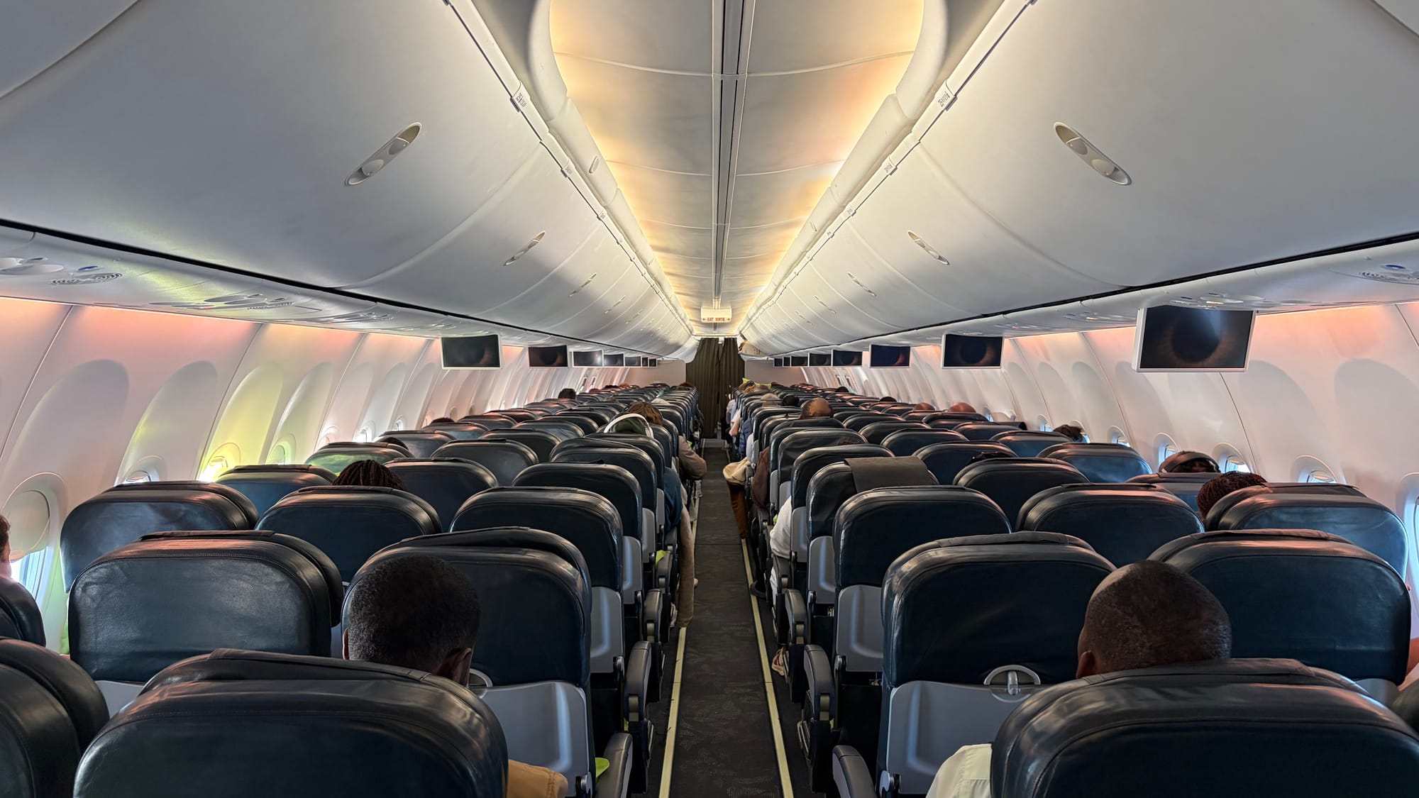 Rows of dark leather economy seats inside a RwandAir Boeing 737 cabin with passengers seated
