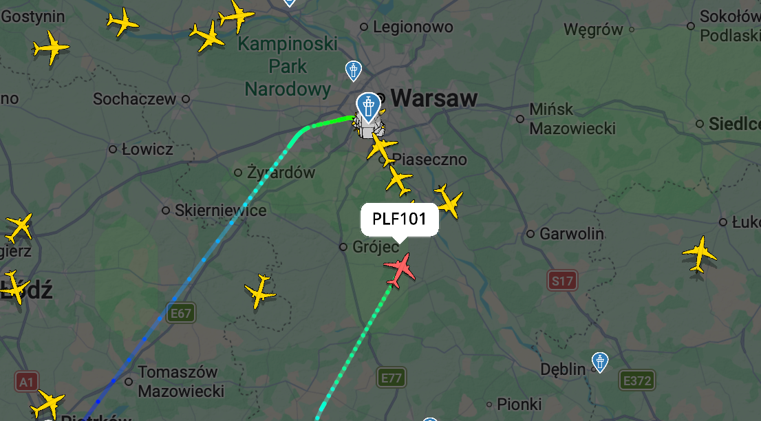 Flight tracking map showing a red plane labeled PLF101 approaching Warsaw from the south, with another plane’s path ending at the airport