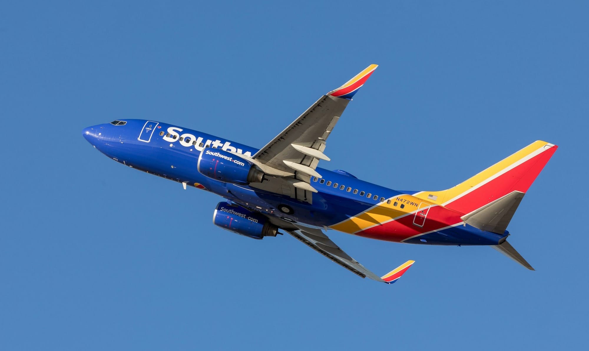 Southwest Airlines Boeing 737 in blue, red and yellow livery climbing against a clear blue sky