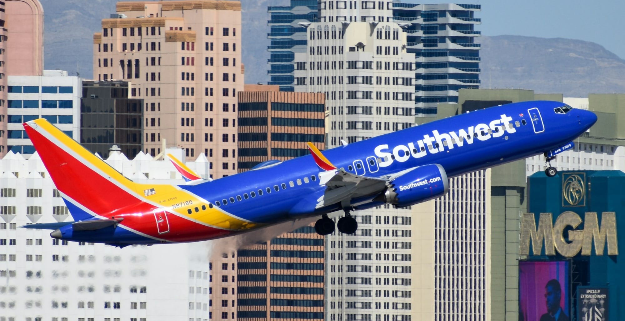 Southwest Airlines Boeing 737 in blue, red and yellow livery climbing past Las Vegas hotel towers and the MGM sign