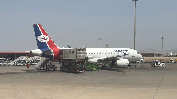 Yemenia Airbus jet in red, white and blue livery parked at Jeddah airport with ground crew and catering truck