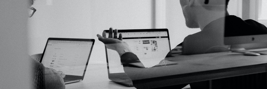Two business men having a meeting while looking at their laptops.