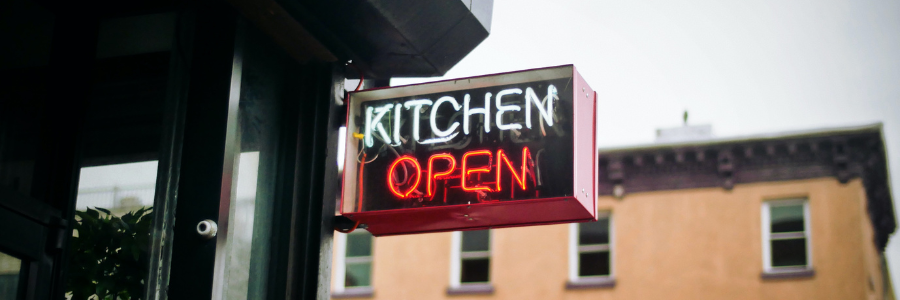 Neon sign reading KITCHEN OPEN.