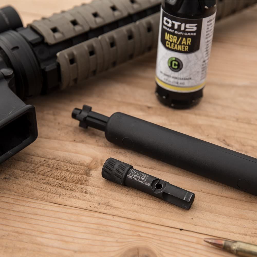 The Otis B.O.N.E. laying beside a rifle and cleaning supplies on a natural wood table