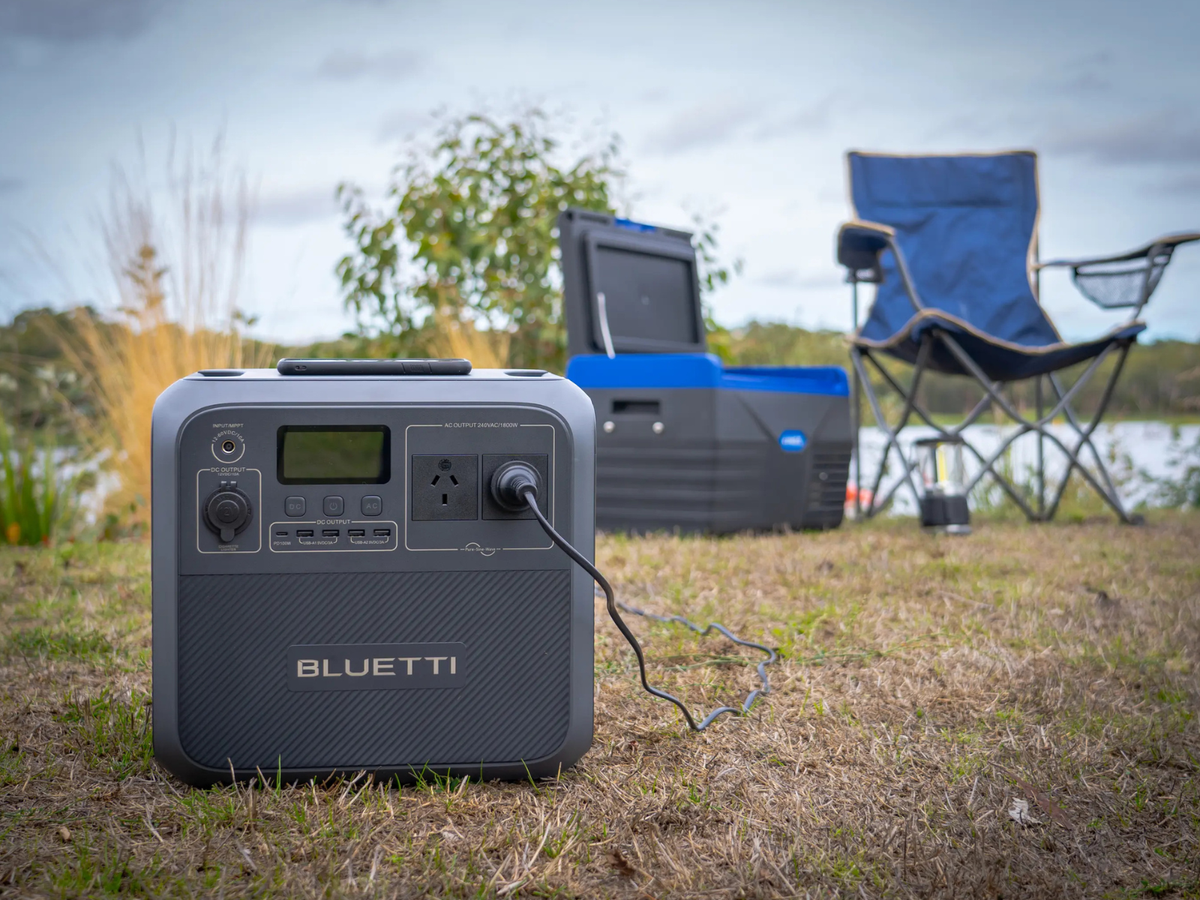 A BLUETTI power station in a camping scenario with a chair next to the water