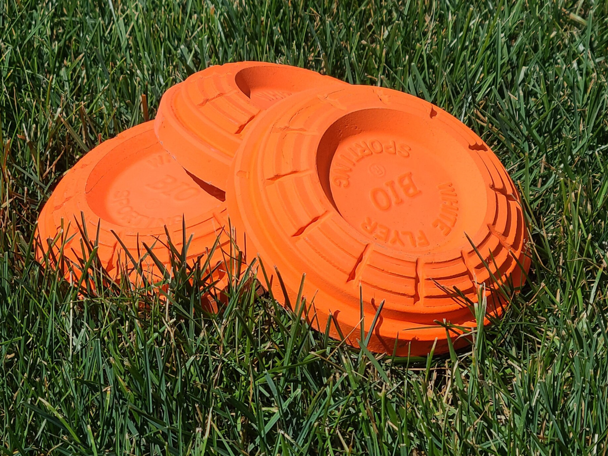 Three clay pigeons laying in grass stacked on top of each other and biodegradable to boot!