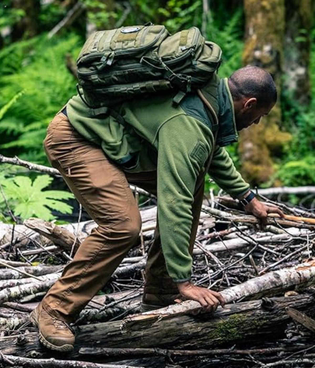 A man in tactical pants attempting to cross a brush pile with 5.11 Apex's