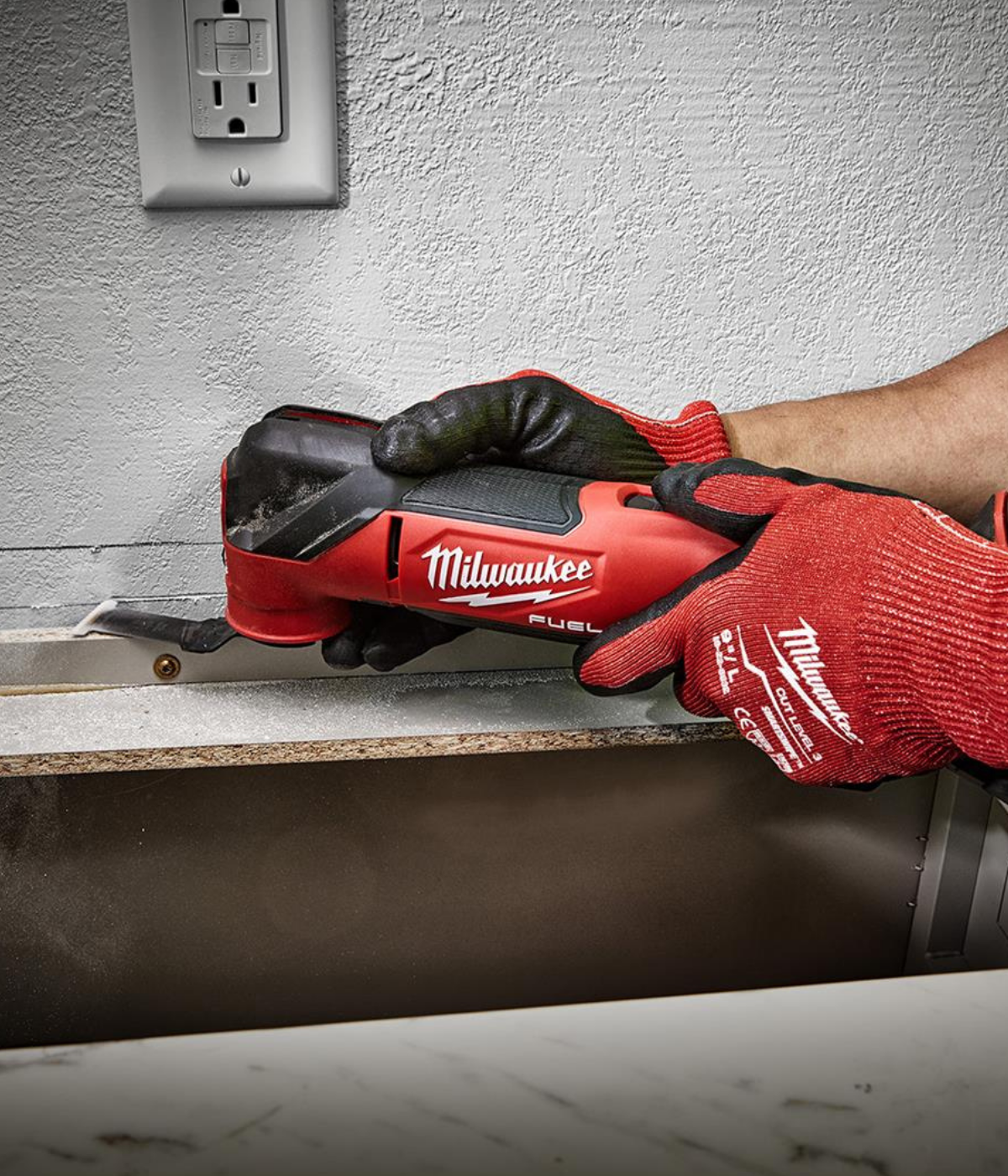 Someone using a multi-tool to cut drywall board for repairs.