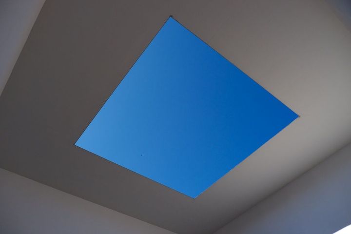 An artists installation in the Kanazawa Museum of Modern Art. A cutout in a ceiling revealing a deep blue sky.