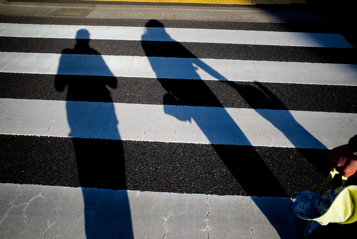Shadows of a family crossing the road
