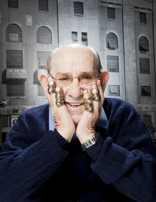Yogi Berra has his hands on his cheeks. He's wearing ten World Series rings on his bilateral pinky and ring fingers.