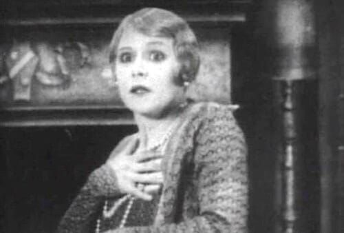 Black-and-white photo of woman clutching pearls.