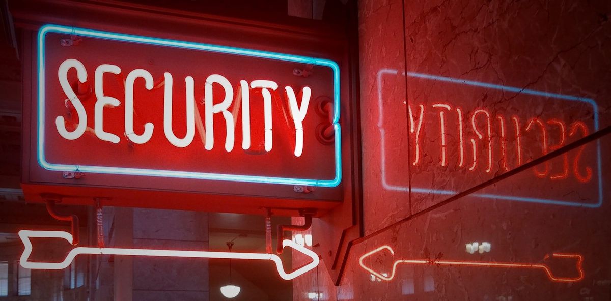 A red neon sign reading “SECURITY” outlined in blue glows indoors, with a matching neon arrow beneath it and the reversed reflection of the sign visible on a polished wall to the right.