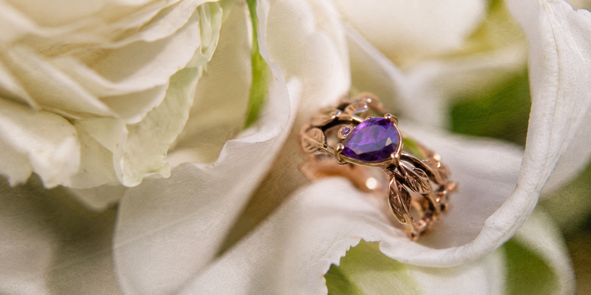 Handcrafted vanya Jewelry ring with a purple gemstone, set among white roses