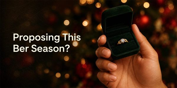 Man's hand holding an open ring box with a nature-inspired engagement ring, festive Christmas bokeh background, "Proposing This Ber Season?