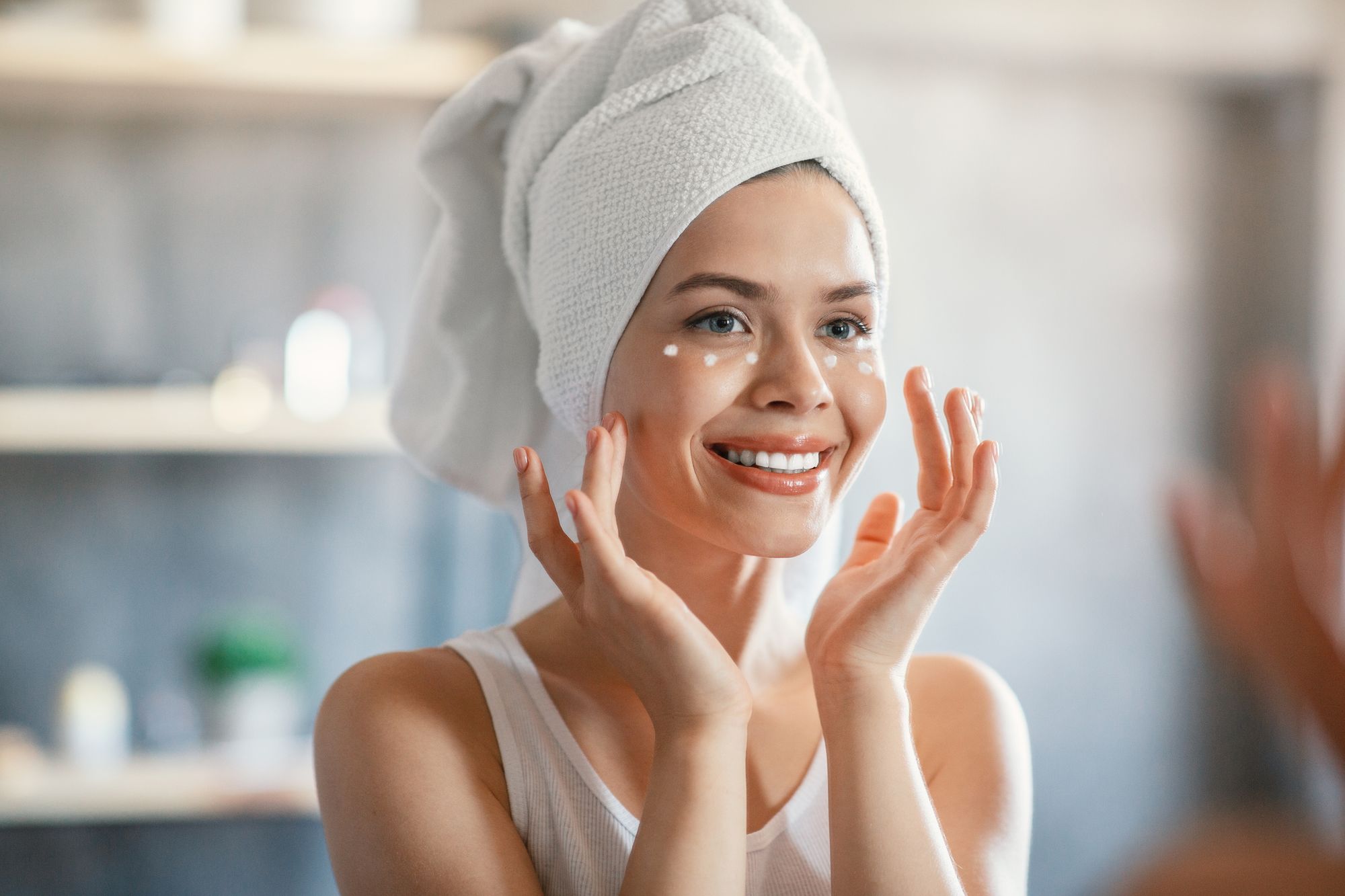 woman putting eye cream on in a mirror