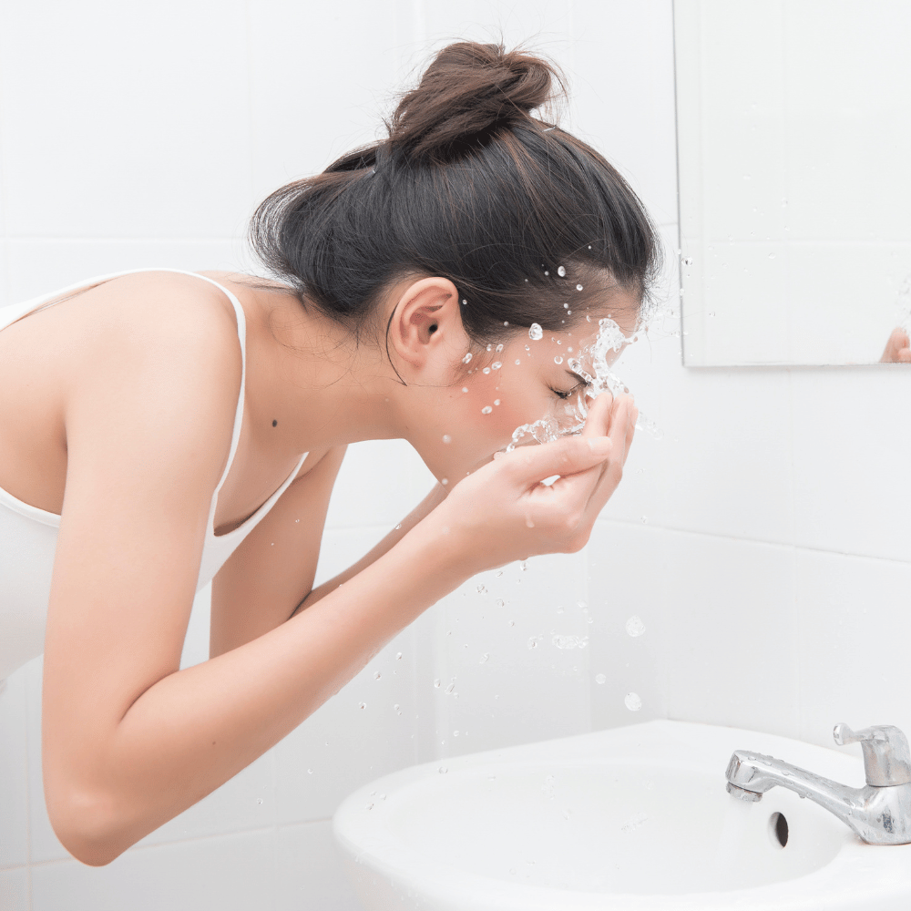 woman washing her face in the sink