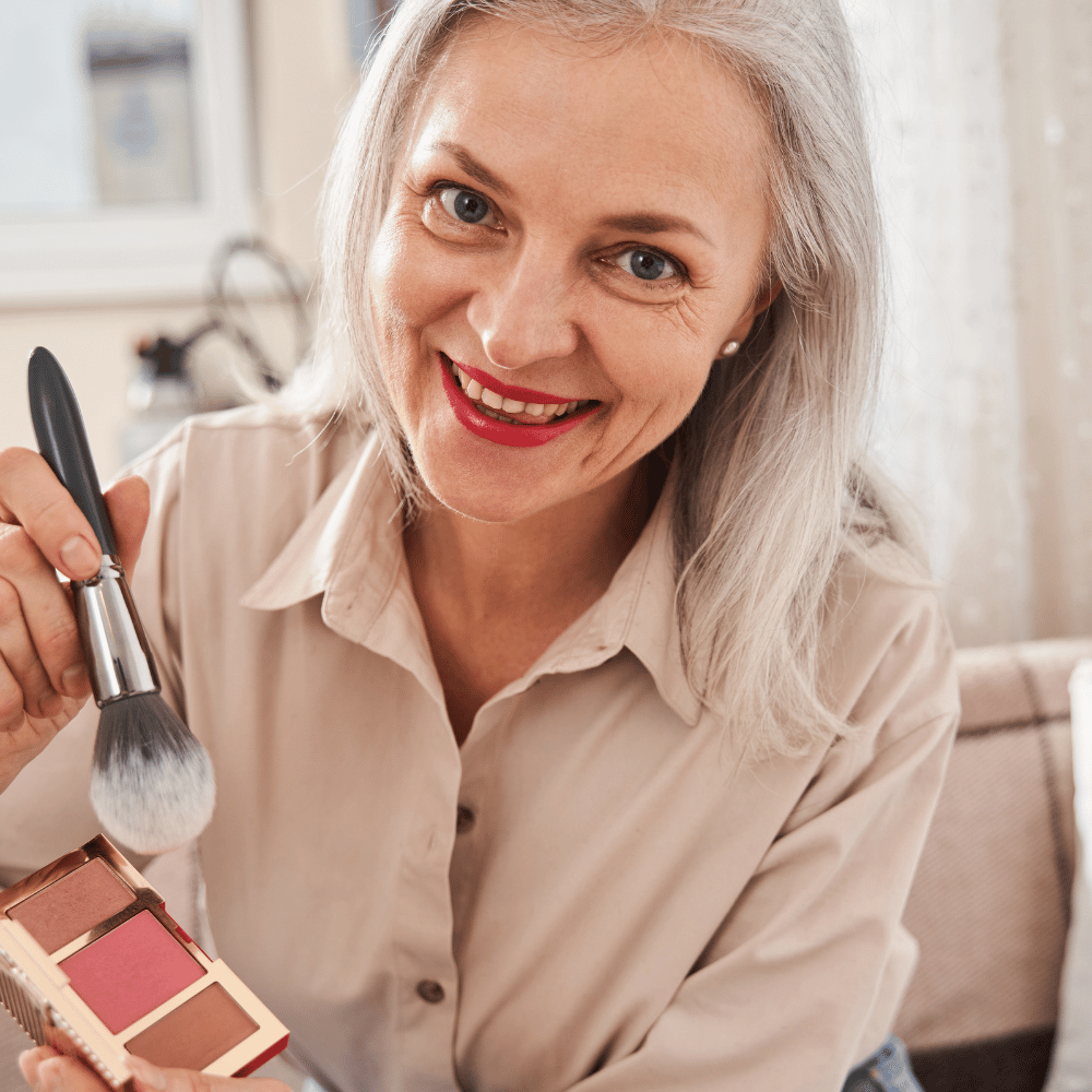 mature woman applying blush in mirror
