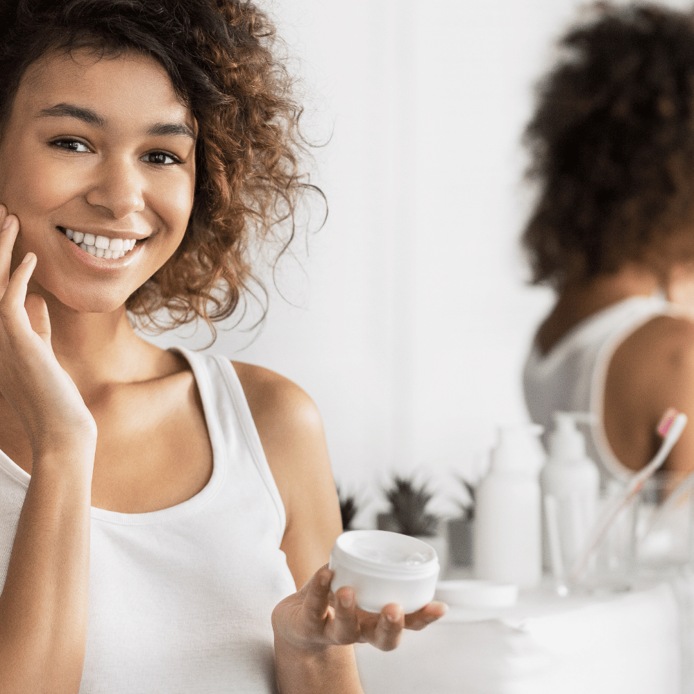 woman moisturizing her face in mirror
