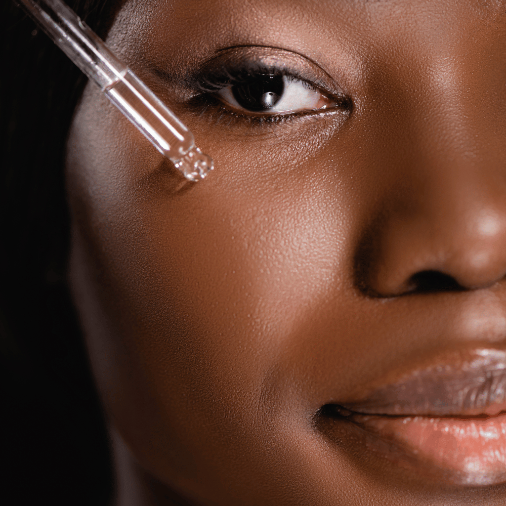 closeup of woman's face applying a serum to face using a dropper