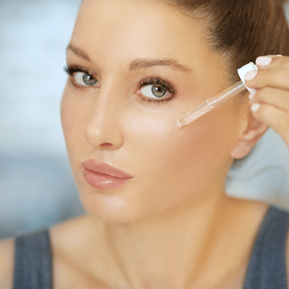 closeup of a woman's face with a dropper held to her cheek