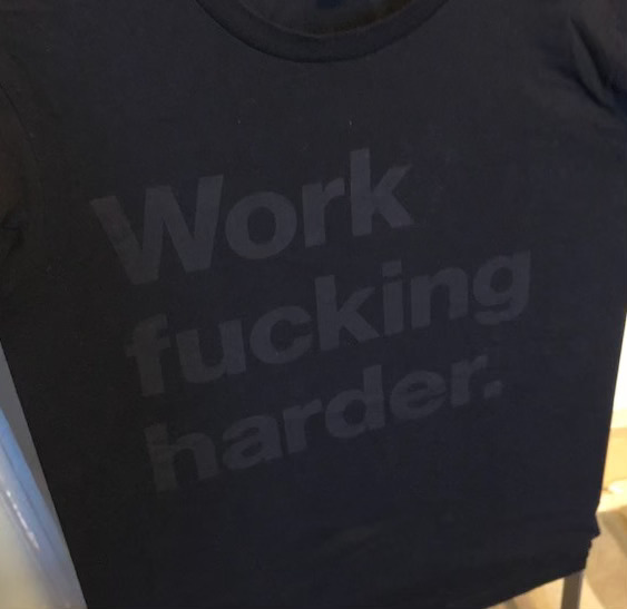 Sort t-skjorte med tekst i grått som sier work fucking harder
