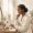  Woman with deep brown skin sitting at a vanity thoughtfully looking at her skincare products
