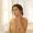 Mediterranean woman with olive skin applying serum near a morning window.
