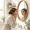 South Asian woman with medium skin examining her face in a bathroom mirror in morning light.