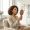 Woman examining her skin in a hand mirror in a clinical consultation room