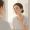 Woman gently pressing a damp cloth to her jawline while looking in a mirror