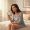 Woman looking into a handheld mirror with a calm, searching expression in morning light