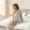 Woman sitting on bed in early morning light looking exhausted