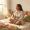 Woman sitting on her bed holding a pill pack with a thoughtful, reflective expression.