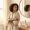 Woman studying her reflection with a searching expression, skincare products pushed to the side.