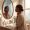 Woman touching her neck and looking in mirror with curious expression