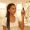Woman with caramel-brown skin holding a serum bottle with an evaluative expression