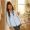 Woman with caramel-brown skin leaning against a doorframe with a mildly impatient expression