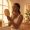 Woman with dark skin checking her skin in a handheld mirror near a window