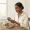 Woman with deep brown skin checking a glucometer at a table with a meal